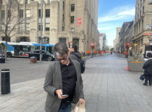 Man looking at phone on a sidewalk